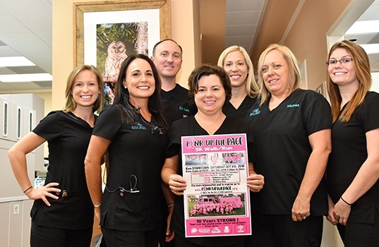 Dental team members holding up a flyer about community events