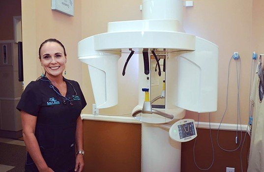 Dental team member standing next to 3 D cone beam scanner