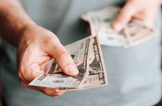 Man’s hands extending cash for payment