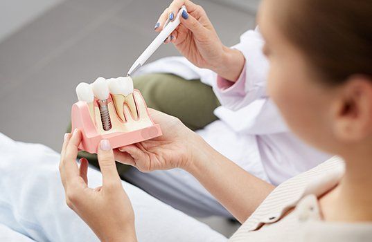 Dentist and patient looking at dental implant model