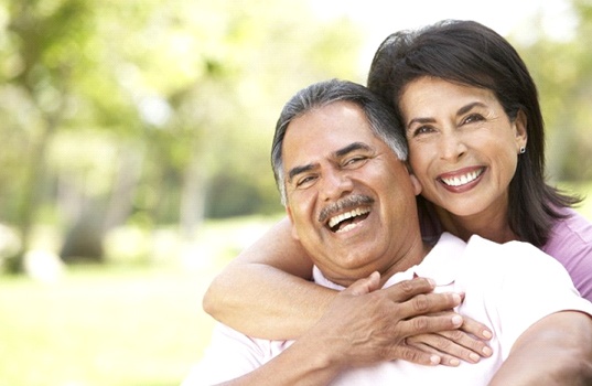 Couple with dentures in St. Augustine laughing in a park