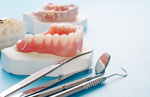 Dentures lying next to dental tools on table