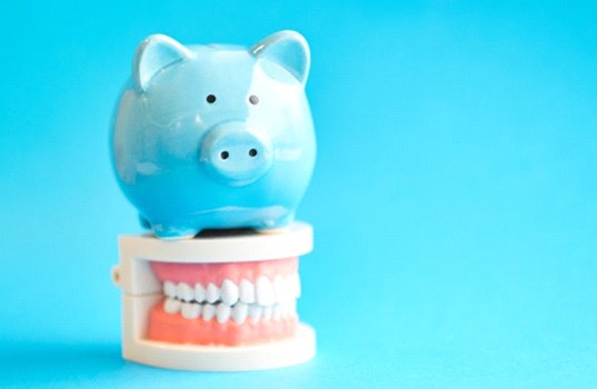 light blue piggy bank sitting atop set of false teeth
