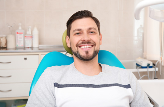 Bearded man sitting in dental chair and smiling