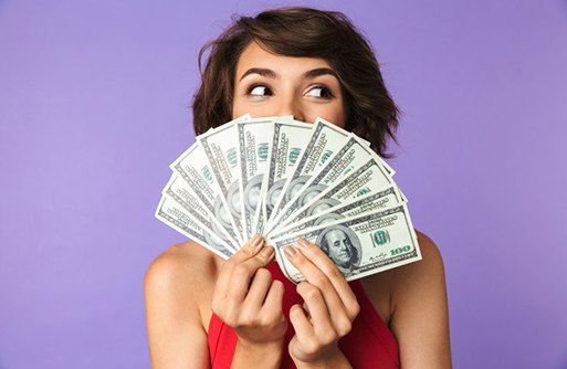 Woman hiding her smile behind a fan of bills