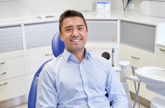 Smiling man in dental office for emergency dentistry