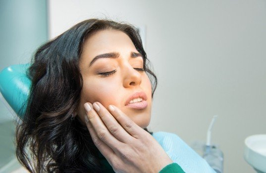 Woman in need of emergency dentistry holding jaw in pain