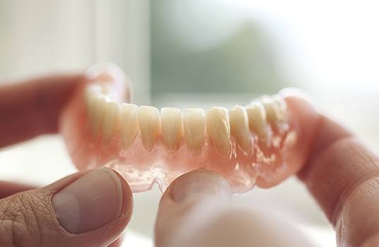 Hand holding a full denture