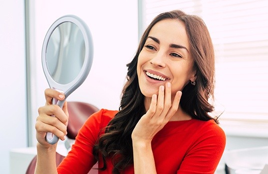 Woman looking at her smile after gum recontouring treatment