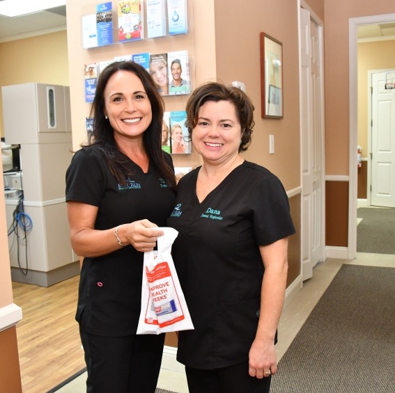 Two dental team members smiling to greet a patient