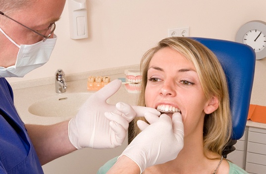A dentist inserting an Invisalign aligner into a female patient’s mouth for the first time