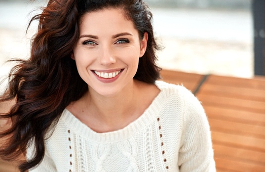 A young woman wearing a white sweater showing off her beautiful, healthy, perfectly aligned smile