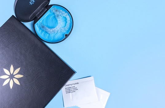 An Invisalign folder, cleaning crystals, and protective case that is holding a set of aligners