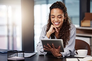 Woman smiling while working on tablet in office
