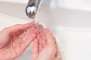Patient rinsing aligners with water in sink