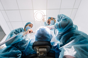 View looking up at two dentists performing oral surgery on patient