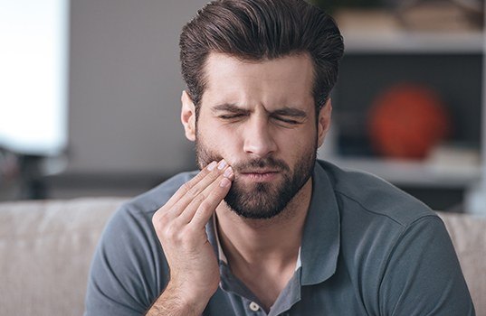 Man in need of root canal holding cheek in pain