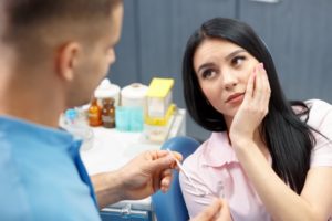 woman in pain talking to her dentist about cracked teeth 