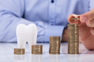 Piles of coins and tooth showing cost of dental implants