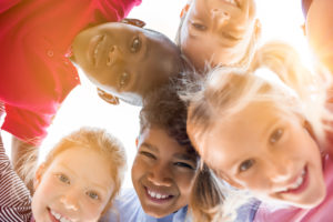 Circle of young children looking down and smiling