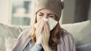 woman wearing a beanie and blowing her nose 