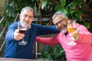 Men holding glasses and eating with dentures