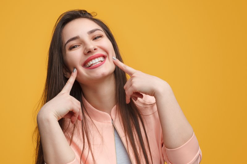 young woman smiling and pointing to teeth