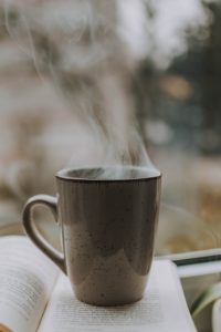 Steaming cup of coffee on a book