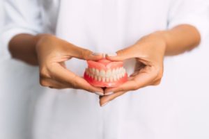 a woman smiling at her dentures with her dentist