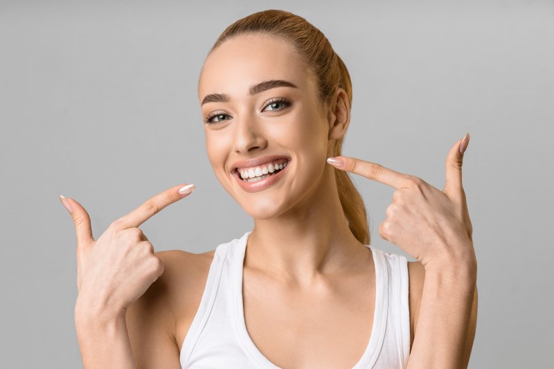 Woman smiling with teeth pointing her index fingers at each side