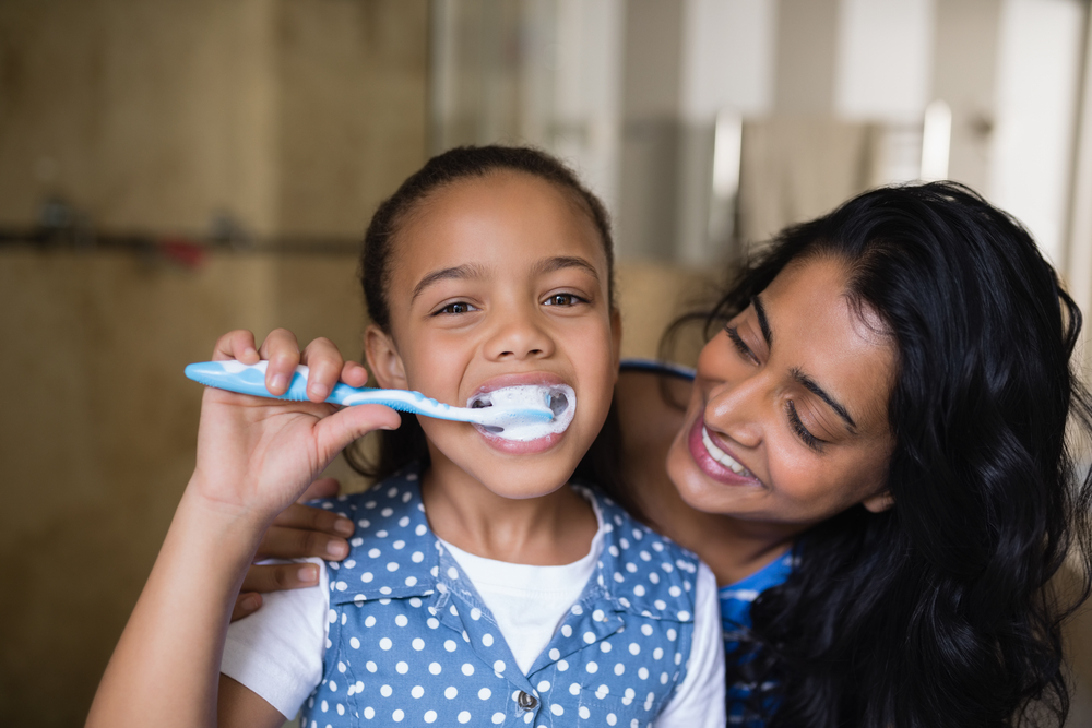 parent helping child brush their teeth