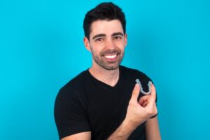 Man smiling while holding his Invisalign tray